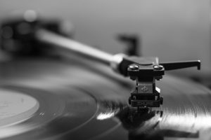 Close-up of a turntable needle on a spinning vinyl record, in black and white.
